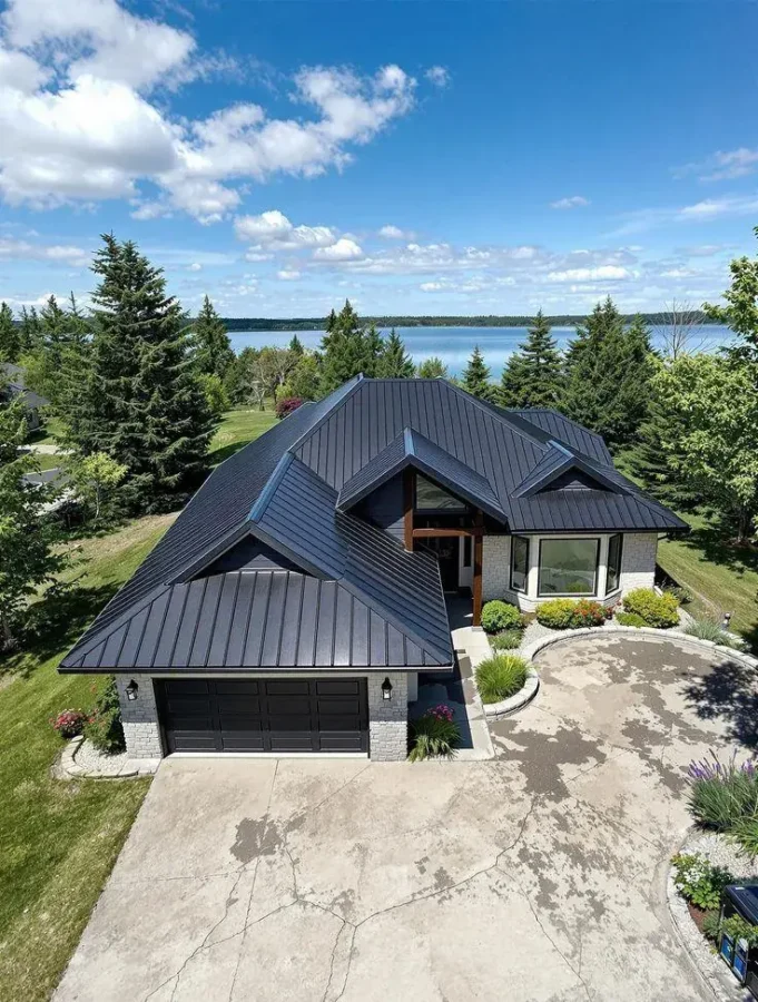 New home with a dark metal roof by a lake